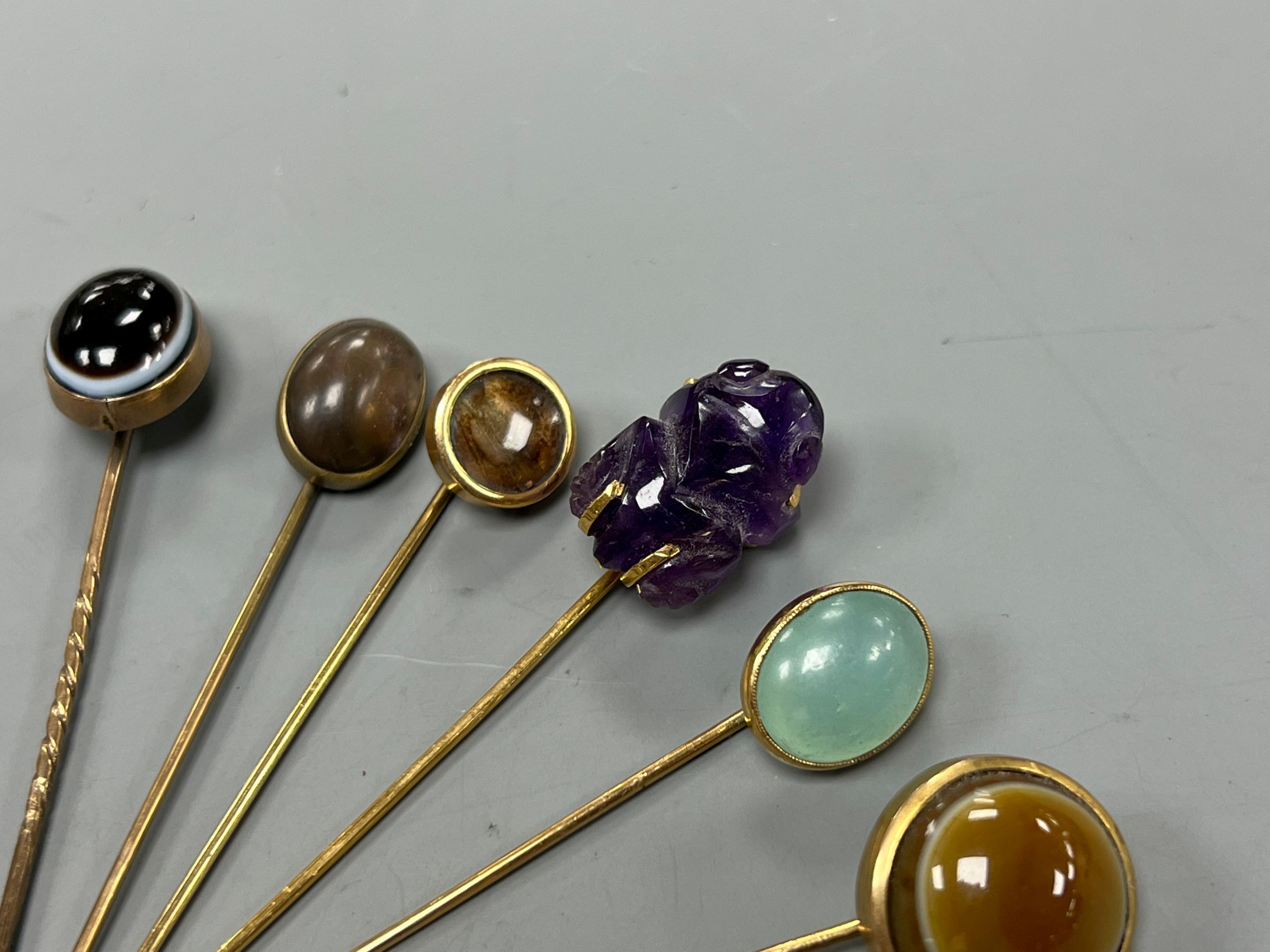 A small collection of eight assorted mainly yellow metal and chalcedony set stick pins, including Scarab, amethyst frog and banded agate